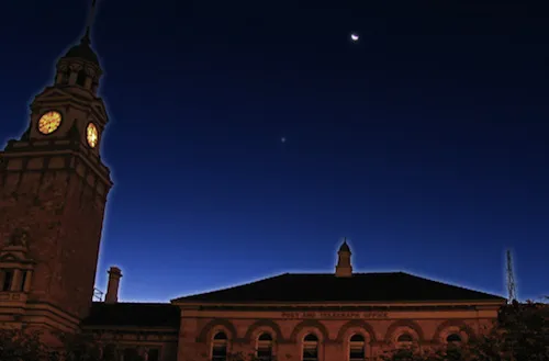 A photo of the moon rising over the Kalgoorlie post and telegraph office.