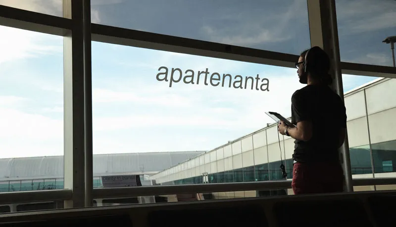 Photo of a man standing near an airport window.
