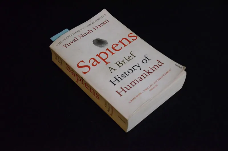 Photo of the book 'Sapiens A Brief History of Humankind' on the top of a table.