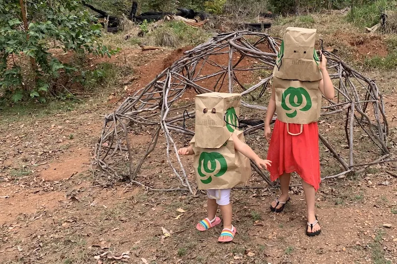 A photo of my children, dressed as robots in front of a 3V geodesic dome made from sticks.