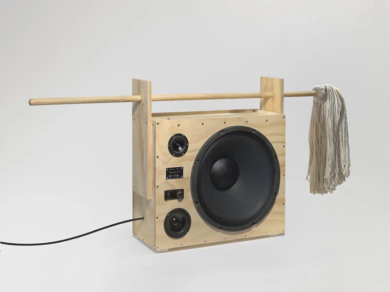 A photo of the plywood Tom Sachs boombox that has a broom for a handle.
