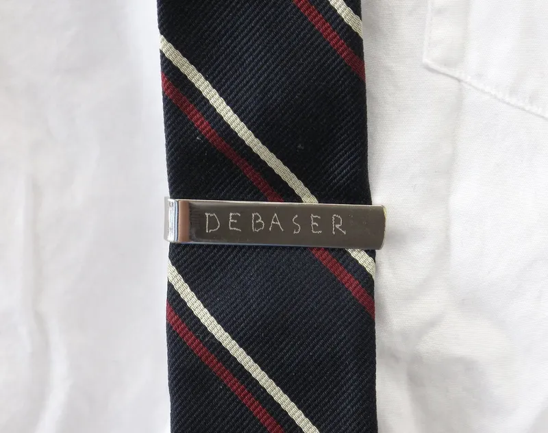 A Tom Sachs tie clip engraved with the word debaser.