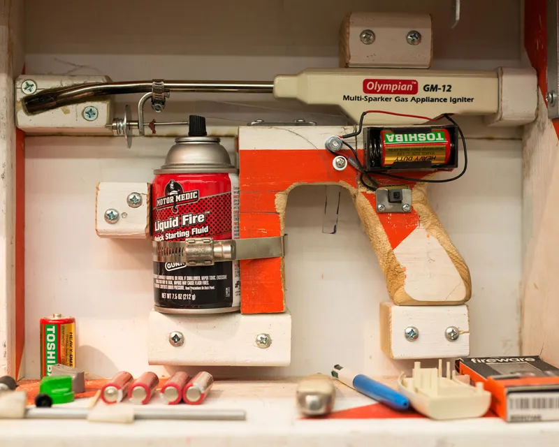 A photo of a Tom Sachs flame thrower mounted in a case.
